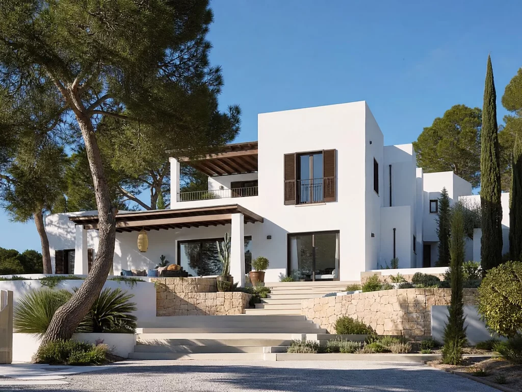 Exterior de una villa de hormigón prefabricada de estilo mediterráneo en Marbella, con paredes blancas nítidas, un porche cubierto con vigas de madera, una terraza superior con un balcón de hierro forjado, y un gran ventanal de vidrio